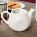 A white Tuxton eggshell china teapot on a table.