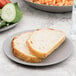 A piece of bread on a 10 Strawberry Street matte gray stoneware plate on a table.