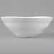 A close-up of a white 10 Strawberry Street stoneware serving bowl with a curved edge.