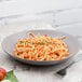 A 10 Strawberry Street matte wave stoneware plate with spaghetti and tomato sauce with a fork.