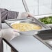 A person holding a Vollrath stainless steel metal tray with food.