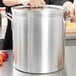 A woman holding a large silver Vollrath stock pot.
