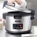 A woman using a Hamilton Beach commercial rice cooker on a white surface.