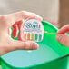 A hand holding a plastic container of Noble Chemical Quaternary Test Papers.