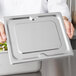 A chef holding a Vollrath stainless steel 1/2 size steam table pan cover.