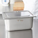 A silver Vollrath Super Pan 3 metal container with a lid on a counter.