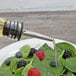 A Choice oil and vinegar cruet pouring oil onto a salad with berries.