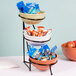 A three tiered Cal-Mil bowl stand with food in it.