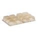 A white plastic candy tray with square shaped objects.