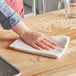 A person using a Choice natural waffle-weave kitchen towel to clean a wooden table.