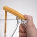 A person using a yellow Matfer Bourgeat automatic dispenser funnel.