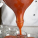 A person using a Matfer Bourgeat automatic dispenser to pour liquid into a glass.