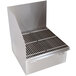 A stainless steel floor mounted mop sink with a metal grate over the drain.
