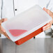A person holding a Flexsil high-heat silicone lid on a plastic container of food.