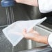 A hand using a Flexsil high-heat silicone lid to cover a plastic container.