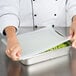 A chef using a Flexsil high-heat silicone lid on a tray of food.