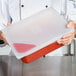 A chef holding a red Flexsil lid over a plastic container.