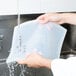 A person washing a Flexsil high-heat silicone lid over a sink.