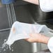 A hand holding a Flexsil high-heat silicone lid over a plastic food pan.