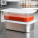 A Flexsil high-heat silicone lid on a metal food pan with red sauce inside.