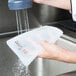 A person washing a Flexsil high-heat silicone lid in a school kitchen.