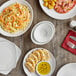 A table with Acopa bright white stoneware plates of pasta and shrimp with a glass of wine.