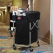 A Rubbermaid laundry cart with a black cover and bag on a metal frame.