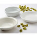 A Tuxton white china pasta bowl on a white surface with pasta and a spoon.