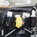 A black bag with a white cap and a black strap containing cleaning supplies.