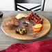 An American Metalcraft melamine serving board with cheese, meat, and grapes on a table.