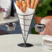 A black metal wire cone basket with 2 white ramekins.