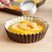 A person using Lucky Leaf Premium Peach Pie Filling to make a pie.