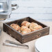 An American Metalcraft small wood crate with food on a table.