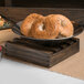 An American Metalcraft small wood crate filled with bagels on a table in a bakery display.