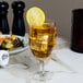 A Reserve by Libbey Contour goblet filled with a lemonade and ice, with a lemon slice on the rim.