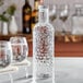 An American Metalcraft pebbled plastic water bottle on a table with a glass of ice water.