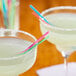 Two glasses of colorful drinks with neon straws on a table.