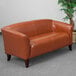 A brown leather Flash Furniture Hercules Imperial loveseat with wooden feet.