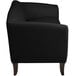 A Flash Furniture black leather sofa with wooden legs.