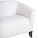 A white Flash Furniture leather sofa with wooden legs.