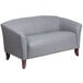 A Flash Furniture gray leather loveseat with wooden legs.