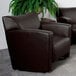 A brown Flash Furniture Hercules Majesty leather chair in a lounge area next to a plant.