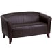 A brown leather Flash Furniture loveseat with wooden legs.