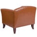 A Flash Furniture brown leather chair with wooden legs.