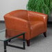 A brown leather Flash Furniture Hercules Imperial chair next to a glass table.