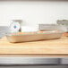 A Vollrath stainless steel hotel pan filled with food on a cutting board.