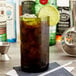 A green Arcoroc wine bottle tumbler with ice tea and a lime wedge.