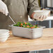 A stainless steel Vollrath hotel pan with food in it.