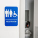 A blue and white Tablecraft ADA restroom sign with a man and woman on it.