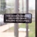 A black and white Tablecraft sign on a door that says "This Door To Remain Unlocked When Building Is Occupied"